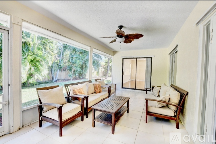 A living room with a ceiling fan and sliding glass doors.