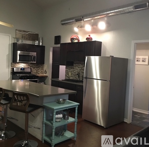 A kitchen with a stainless steel refrigerator and a blue bar stool.