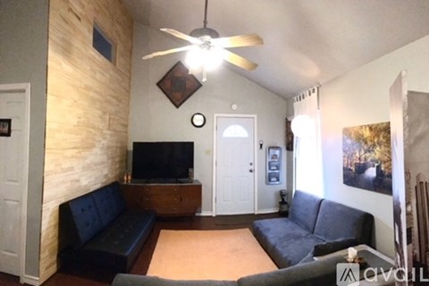 A living room with a black couch and a flat screen TV.