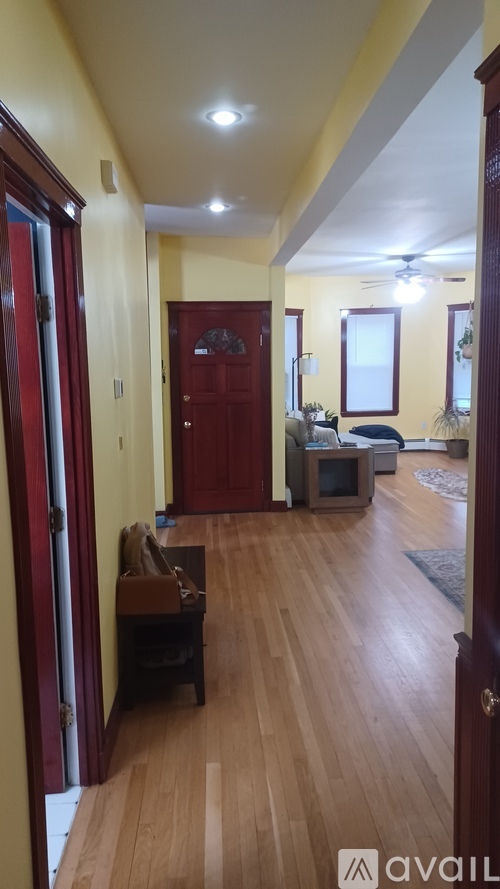 A hallway with a red door and a brown bench.