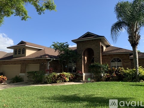 A house with a brown roof and a palm tree in front.