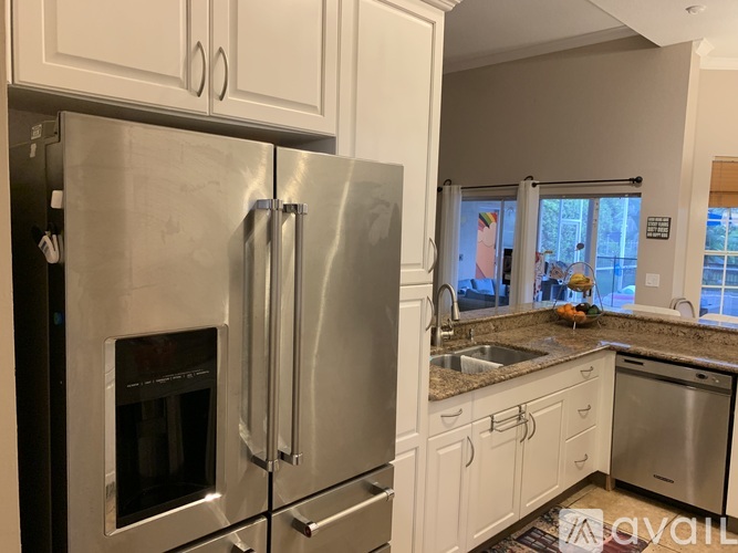 A kitchen with a stainless steel refrigerator and white cabinets.