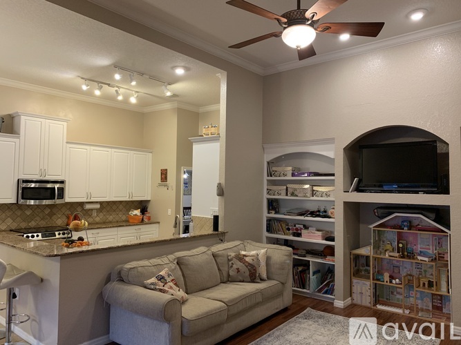 A living room with a grey couch and a ceiling fan.