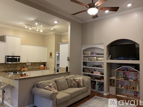 A living room with a grey couch and a ceiling fan.