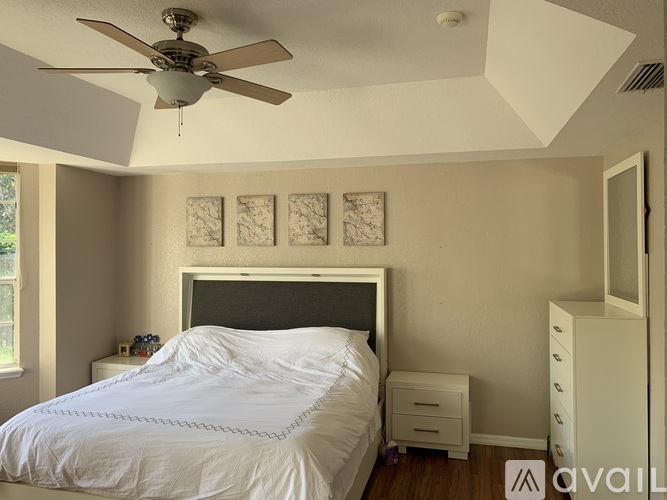 A bedroom with a bed, nightstand, and a ceiling fan.