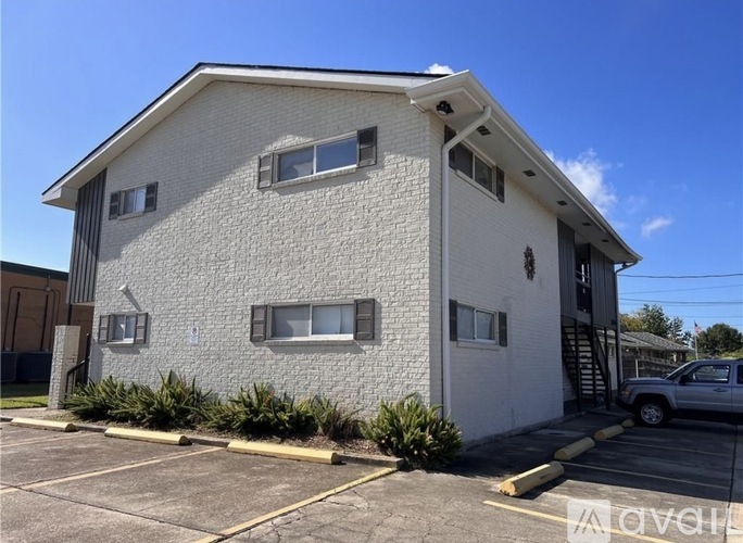 A white building with a parking lot in front.