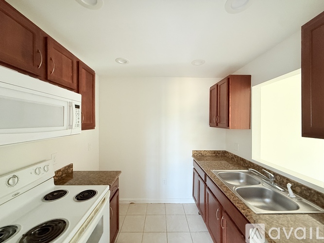 A kitchen with white appliances and brown cabinets.
