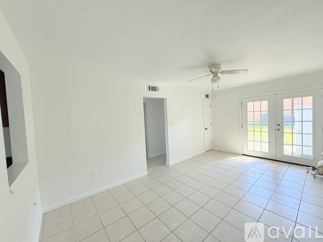 A spacious room with a ceiling fan and tiled flooring.