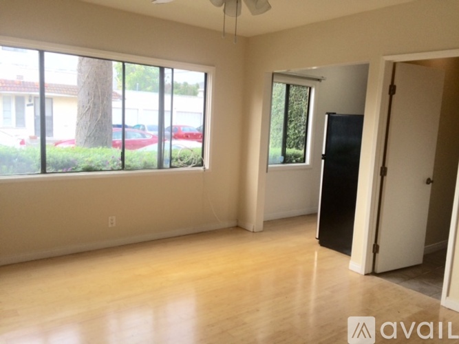A spacious room with a large window and a door leading to another room.