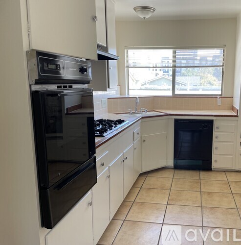 A kitchen with black appliances and white cabinets.