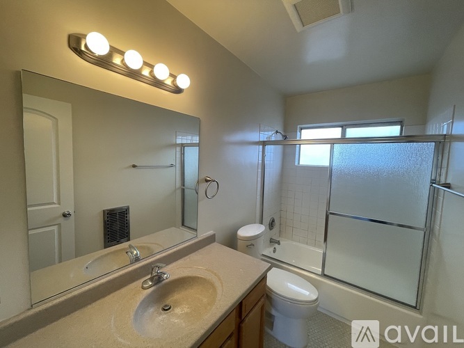 A bathroom with a sink, mirror, toilet, and shower.