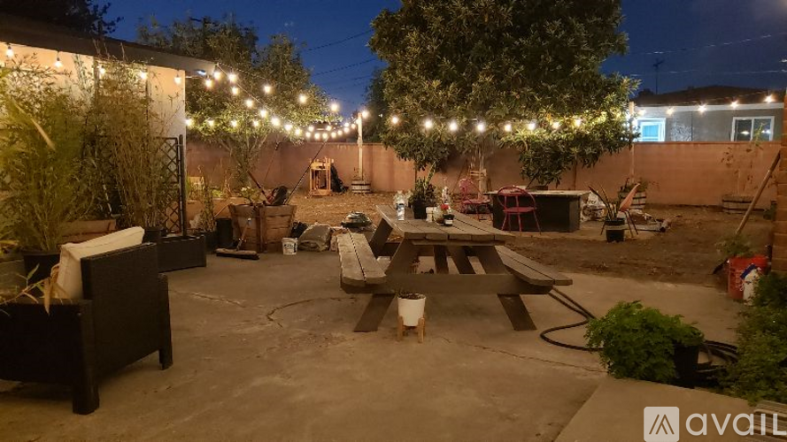 A backyard patio with a table and chairs under string lights.