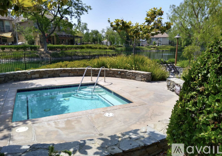A small pool surrounded by a stone wall and a metal fence.