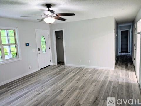 A room with a ceiling fan and wooden flooring.