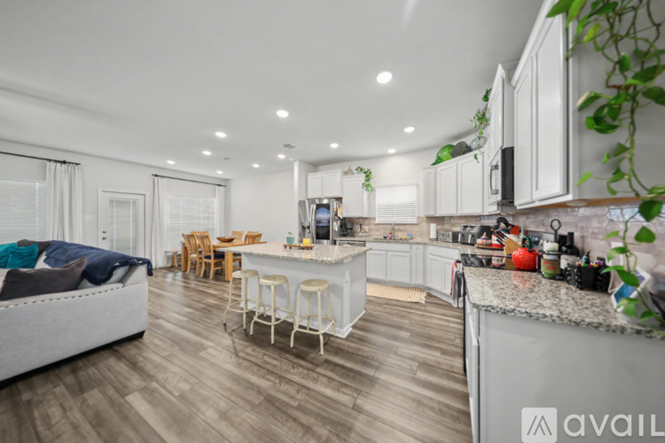 A modern kitchen with white cabinets and a wooden floor.