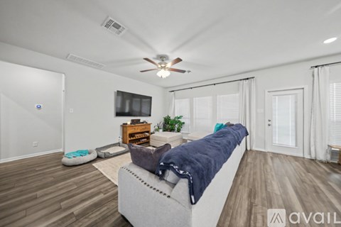 A living room with a grey couch and a ceiling fan.