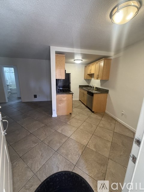 A kitchen with a black fridge and a black stove top.