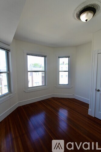 A room with wooden floors and three windows.