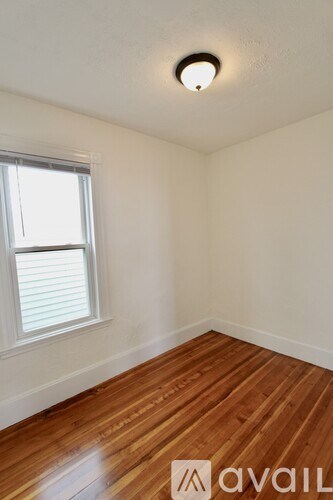 A room with wooden flooring and a window with blinds.