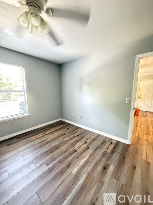 A room with a ceiling fan and wooden flooring.