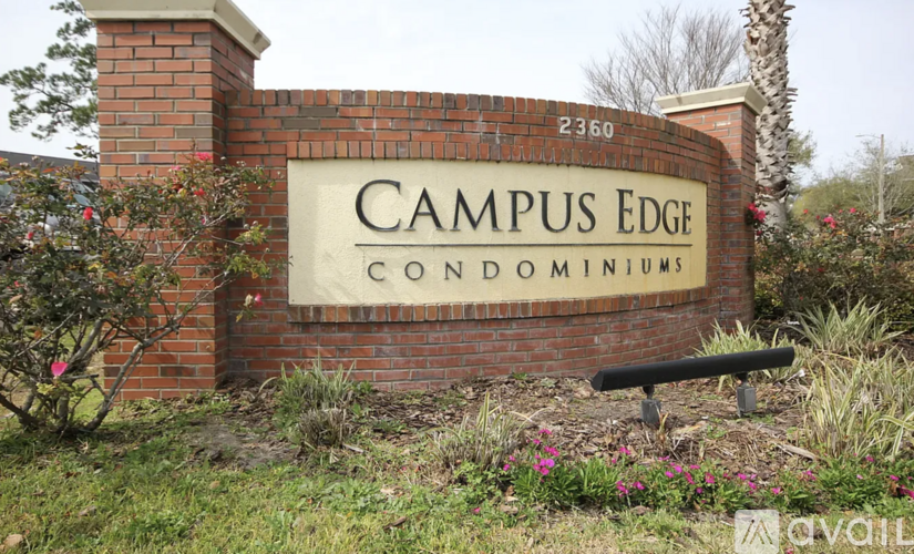 A brick sign that says "Campus Edge Condominiums" in front of a tree.
