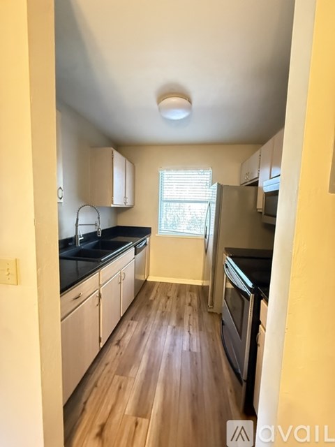 A kitchen with wooden floors and white cabinets.