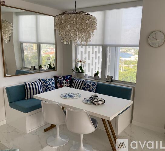 A dining room with a white table and chairs, a blue couch, and a chandelier.