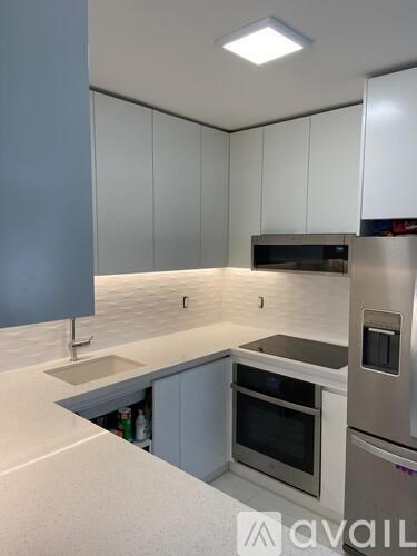 A kitchen with white cabinets and a stainless steel refrigerator.
