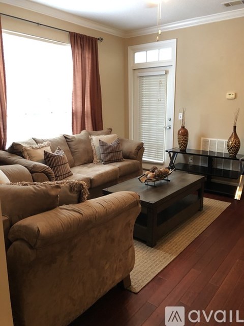 A living room with a brown sofa and a glass coffee table.