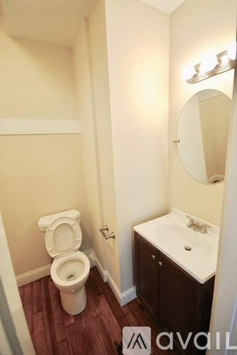 A bathroom with a toilet, sink and mirror.