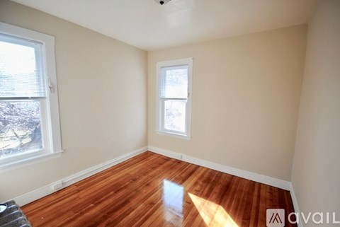 A room with wooden floors and two windows.