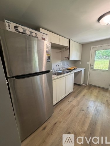 A kitchen with a stainless steel refrigerator and wooden floors.