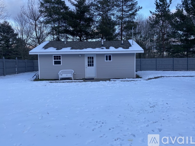 A house with a grey roof and a grey fence is surrounded by snow.