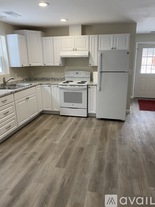 A kitchen with white appliances and wooden floors.