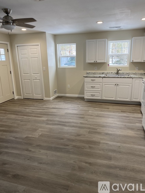 A kitchen with white cabinets and a fan on the ceiling.