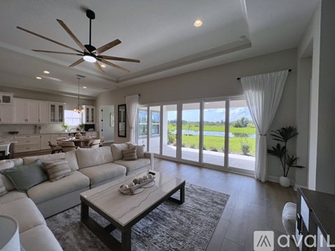 A spacious living room with a large couch and a ceiling fan.