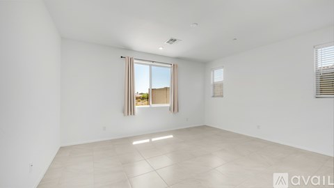 A spacious empty room with a large window and tiled floor.