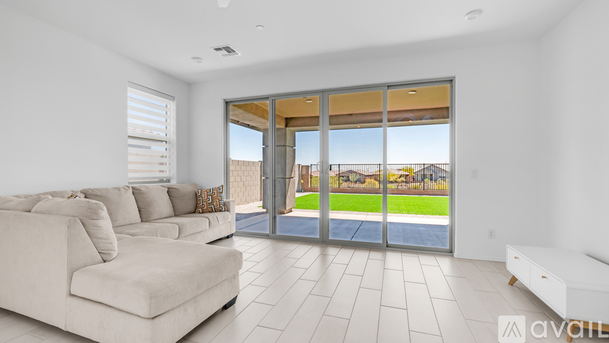 A spacious living room with a large couch and sliding glass doors that open to a backyard.