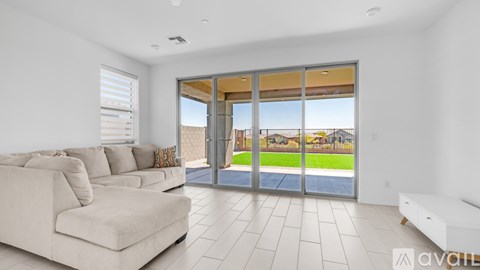 A spacious living room with a large couch and sliding glass doors that open to a backyard.