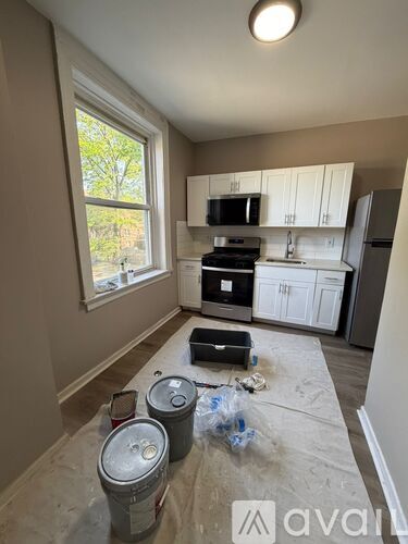 A kitchen with white cabinets and appliances is under renovation.