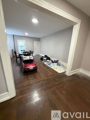 A room with a red car and a dining table.