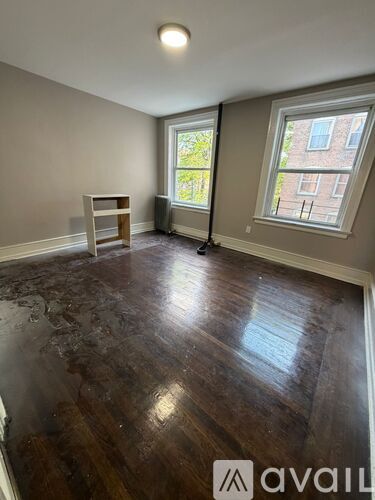 A room with wooden floors and a window overlooking a brick building.