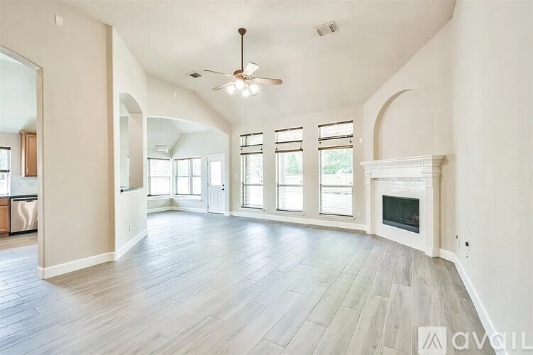 A spacious living room with a fireplace and a fan.