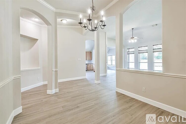 A spacious room with wooden floors and a chandelier hanging from the ceiling.