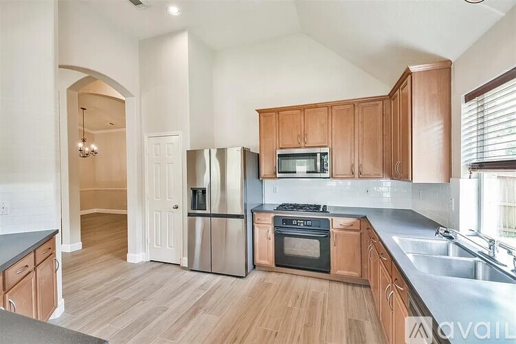 A kitchen with wooden cabinets and stainless steel appliances is available for rent.