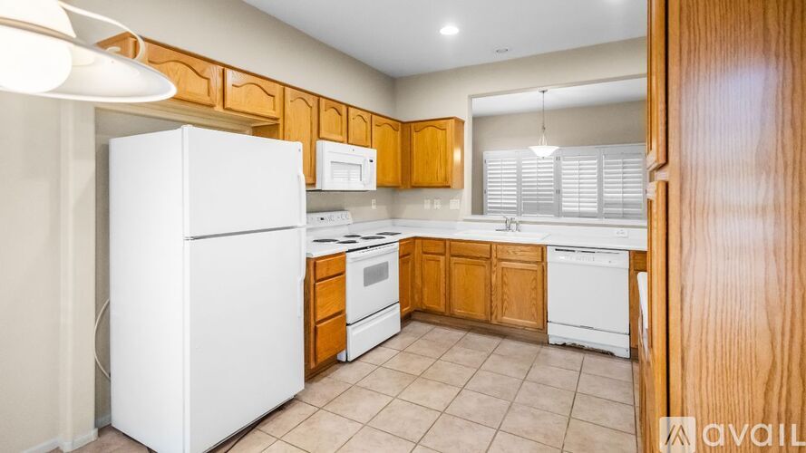 A kitchen with white appliances and wooden cabinets.