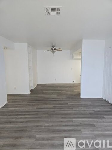 A room with a ceiling fan and wooden flooring.