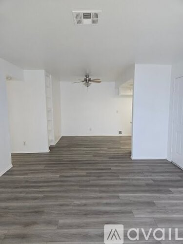 A room with a ceiling fan and wooden flooring.