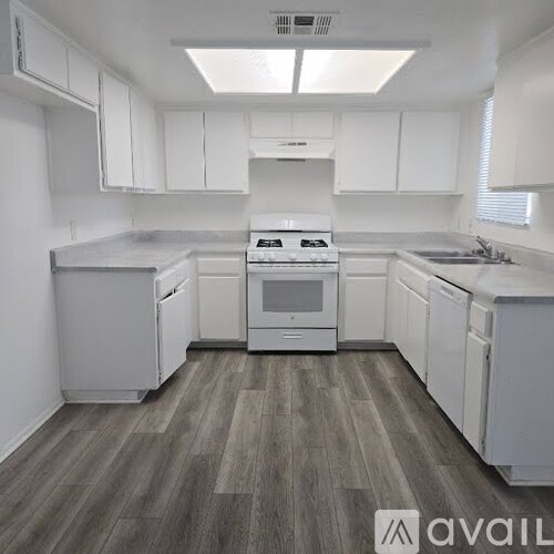 A kitchen with white cabinets and a wood floor.