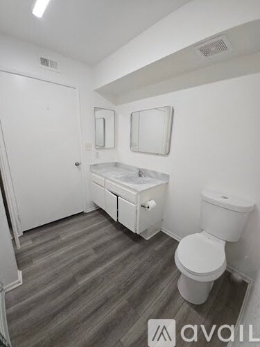 A bathroom with a toilet, sink, and mirror.